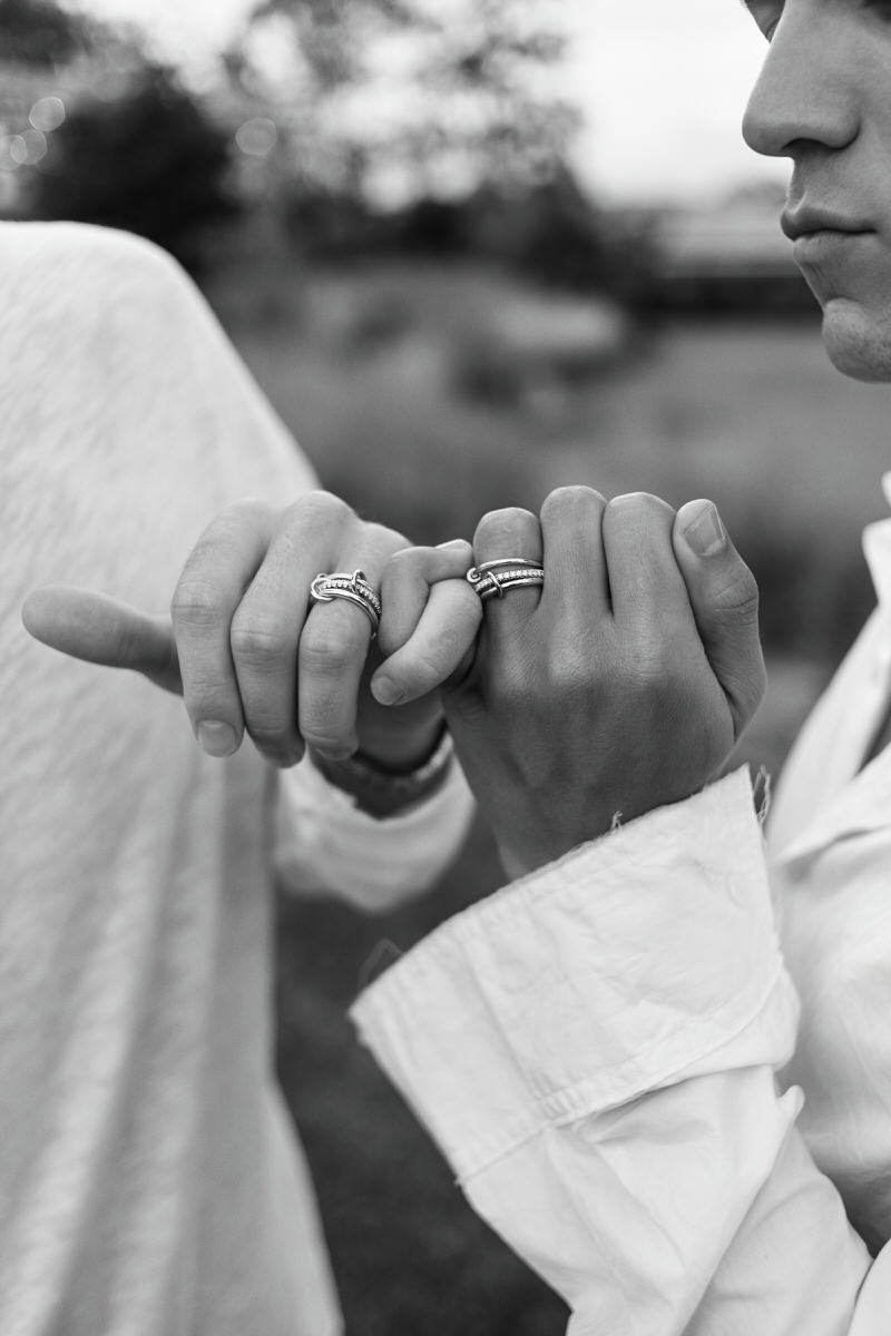 Close-up of Spinelli Kilcollin rings on intertwined hands